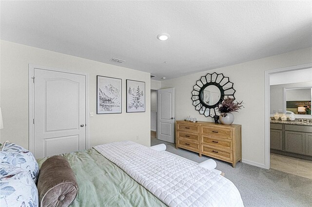 bedroom with light colored carpet and ensuite bathroom