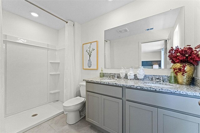 bathroom with tile patterned floors, walk in shower, vanity, and toilet