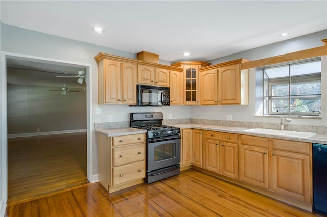 kitchen with light stone counters, ceiling fan, sink, light hardwood / wood-style flooring, and black appliances