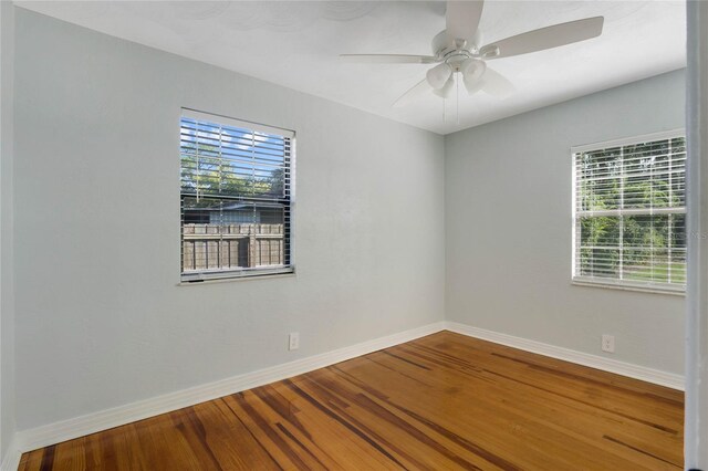 spare room with plenty of natural light, wood-type flooring, and ceiling fan