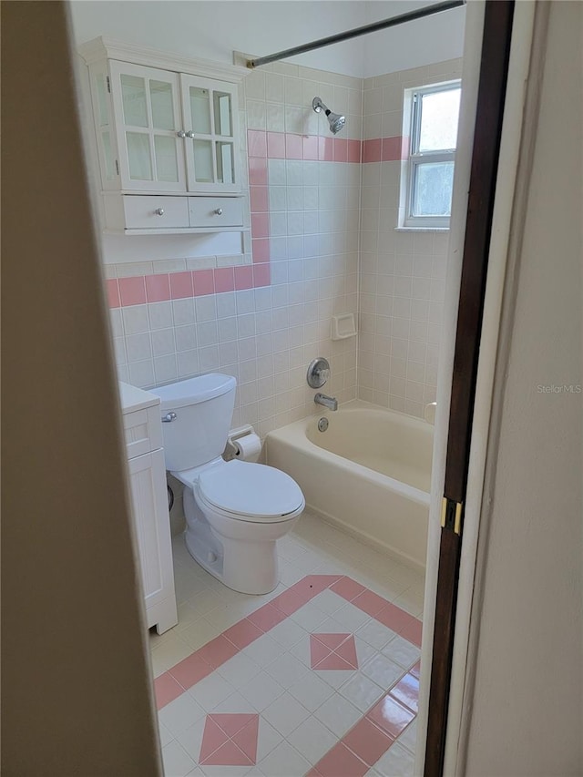 bathroom with tile walls, tiled shower / bath combo, toilet, and tile patterned floors