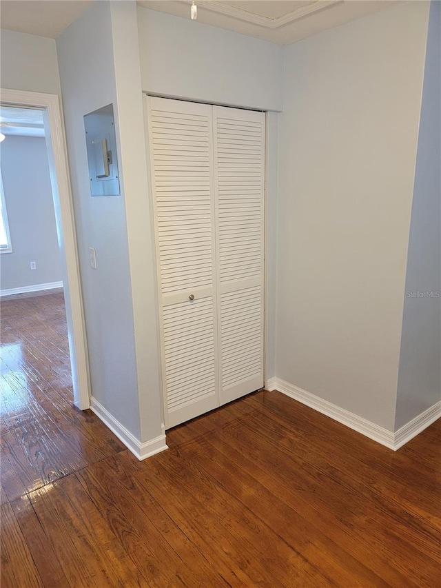 unfurnished bedroom with electric panel, a closet, and hardwood / wood-style floors