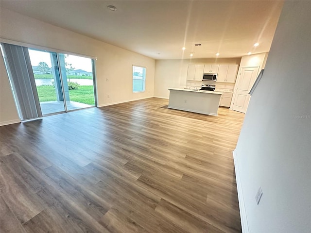 unfurnished living room with baseboards, recessed lighting, and light wood finished floors