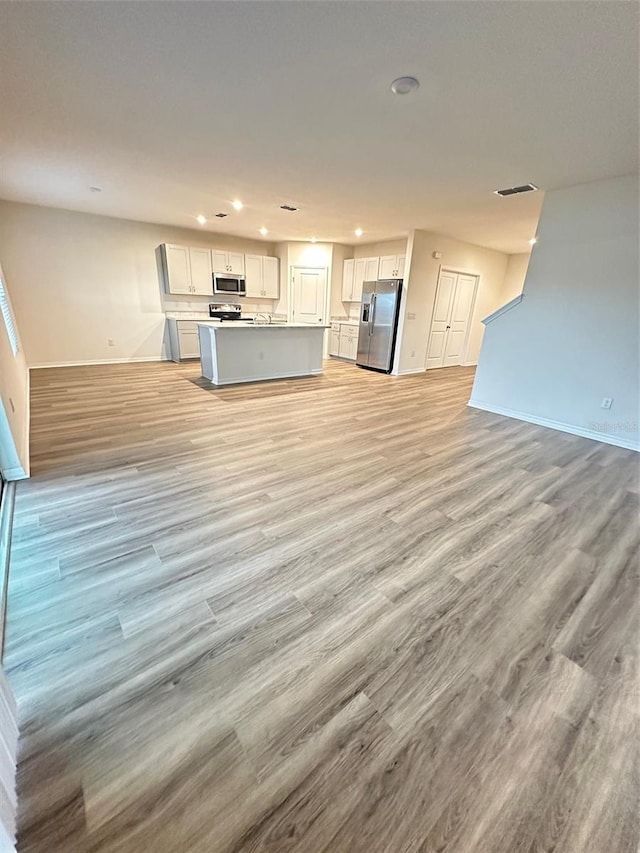 unfurnished living room with baseboards, visible vents, light wood finished floors, and recessed lighting