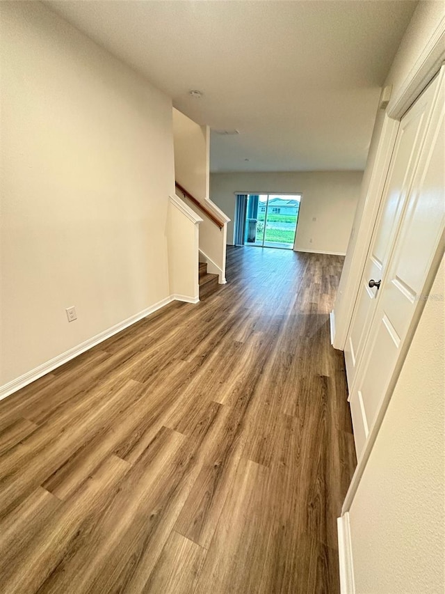 unfurnished living room with wood finished floors, baseboards, and stairs