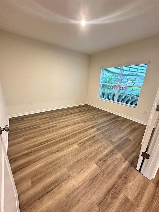 spare room featuring wood finished floors and baseboards