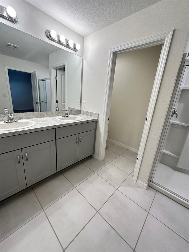 bathroom featuring a stall shower, double vanity, a sink, and visible vents
