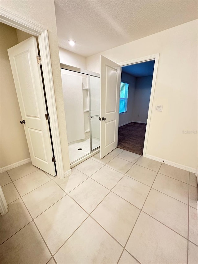 interior space featuring a textured ceiling, a barn door, a closet, light tile patterned floors, and baseboards