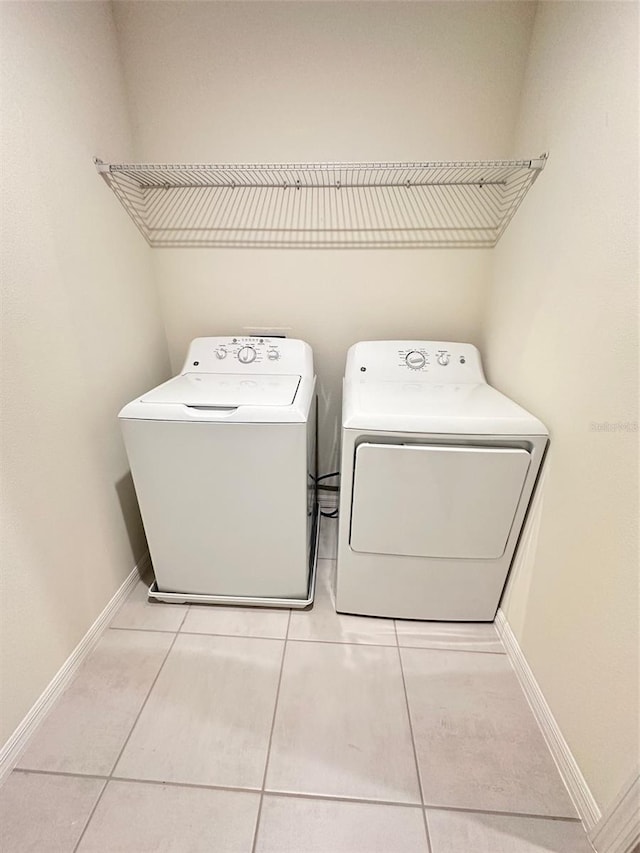 clothes washing area with tile patterned floors, independent washer and dryer, laundry area, and baseboards