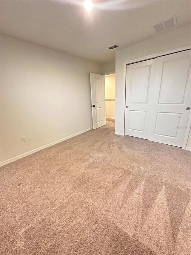 unfurnished bedroom with visible vents, a closet, carpet flooring, and baseboards