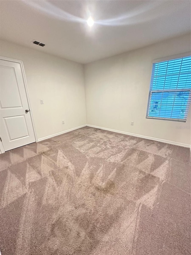 spare room featuring baseboards, visible vents, and carpet floors
