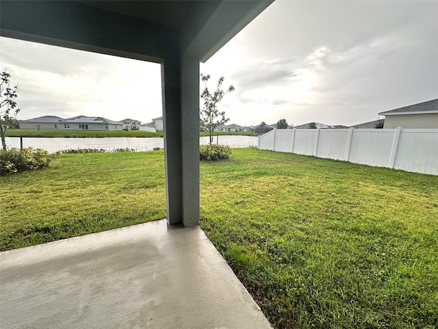 view of yard with fence, a water view, and a residential view