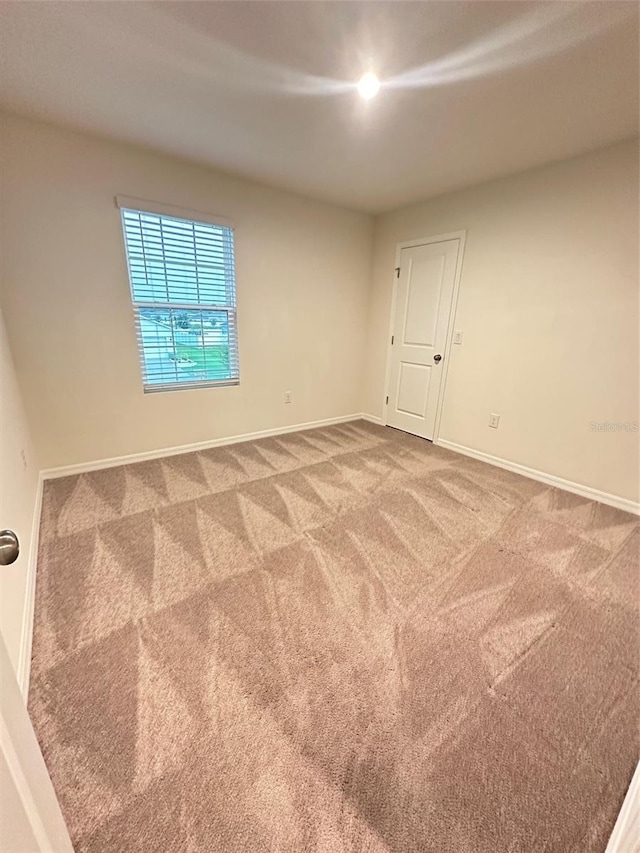 carpeted spare room featuring baseboards