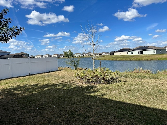 view of yard featuring a residential view, a water view, and fence