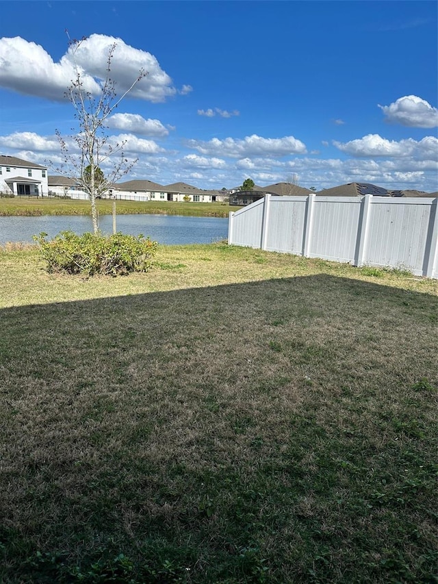 view of yard featuring a water view and fence