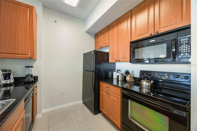 7383 Universal Blvd Unit 710, Orlando, FL 32819 - kitchen with brown cabinetry, baseboards, dark stone countertops, light tile patterned floors, and black appliances