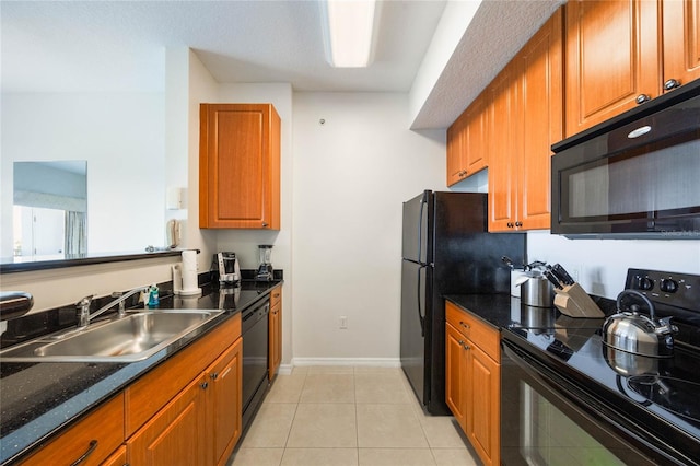 kitchen featuring dark stone countertops, light tile patterned flooring, sink, and black appliances