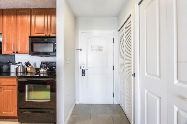 7383 Universal Blvd Unit 710, Orlando, FL 32819 - kitchen featuring dark countertops, tile patterned flooring, brown cabinets, baseboards, and black appliances
