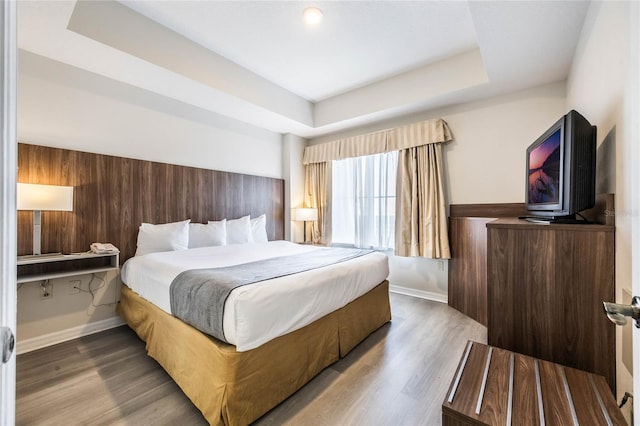 bedroom with hardwood / wood-style flooring and a raised ceiling