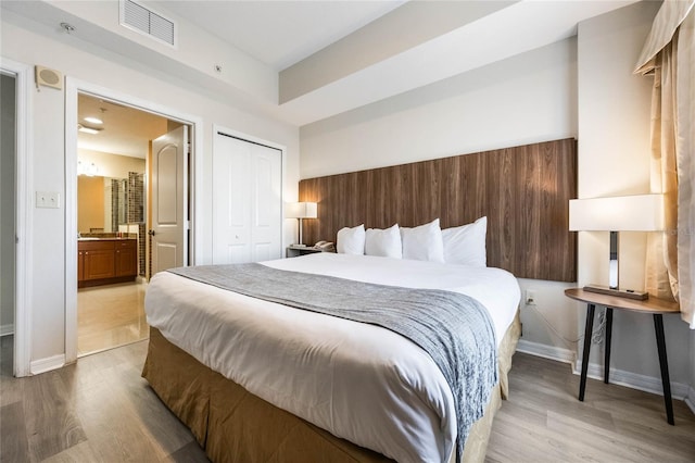 bedroom with light wood-type flooring, a closet, and connected bathroom