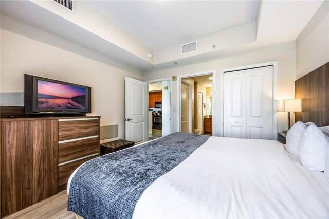 7383 Universal Blvd Unit 710, Orlando, FL 32819 - bedroom with visible vents, connected bathroom, wood finished floors, and a closet