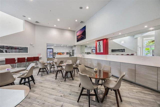 dining area featuring a high ceiling and light hardwood / wood-style flooring