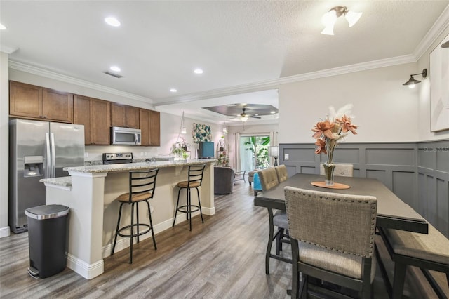 dining room featuring a textured ceiling, ceiling fan, hardwood / wood-style flooring, and crown molding