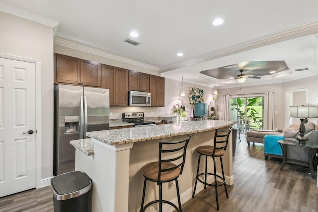 kitchen with a breakfast bar, a center island, stainless steel appliances, dark hardwood / wood-style flooring, and ceiling fan