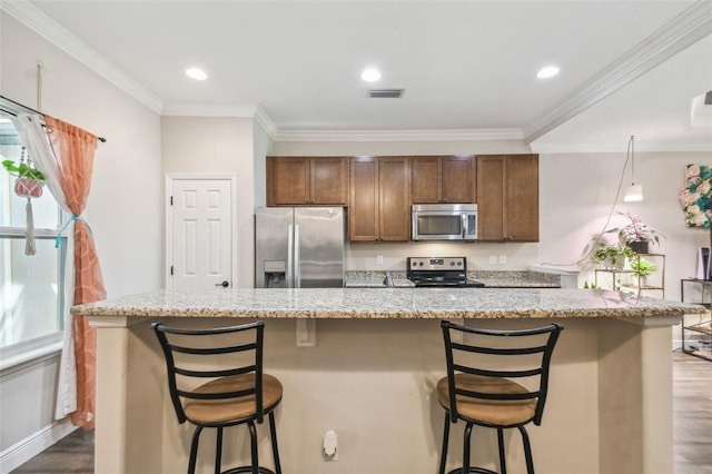 kitchen featuring a kitchen island, dark wood-type flooring, stainless steel appliances, a breakfast bar, and crown molding