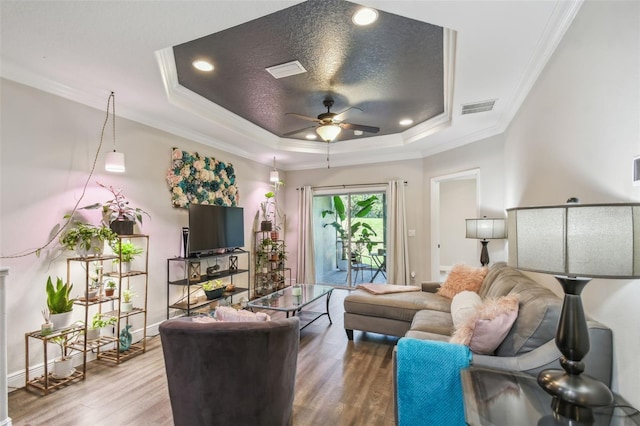 living room with ceiling fan, hardwood / wood-style flooring, a raised ceiling, and ornamental molding