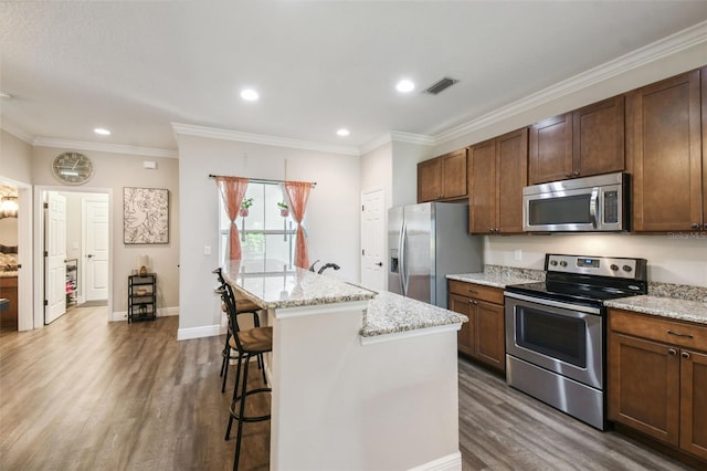 kitchen with appliances with stainless steel finishes, a breakfast bar area, a center island, and dark hardwood / wood-style flooring