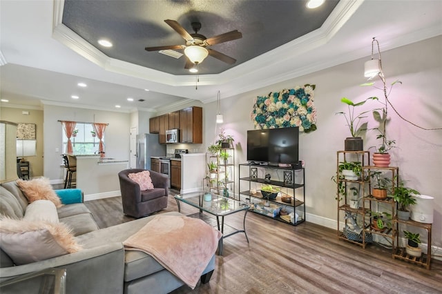 living room featuring ornamental molding, a raised ceiling, and hardwood / wood-style flooring