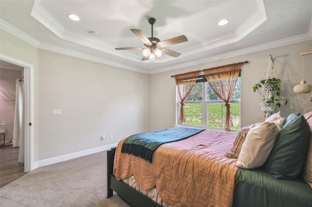 carpeted bedroom with crown molding, ceiling fan, and a raised ceiling