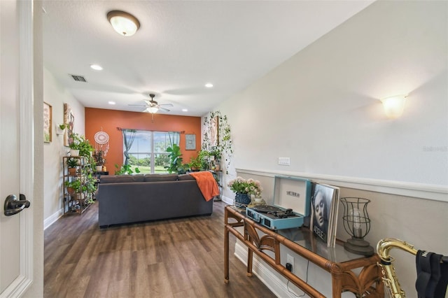 living room featuring ceiling fan and dark hardwood / wood-style flooring