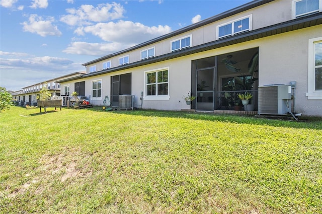 rear view of property with a lawn, cooling unit, and a sunroom