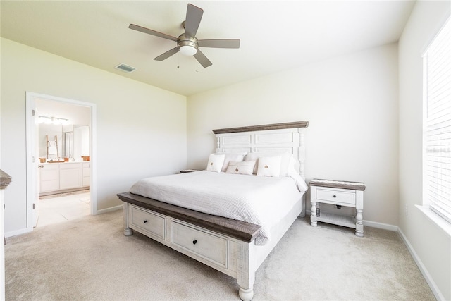 carpeted bedroom featuring ceiling fan, ensuite bathroom, and multiple windows