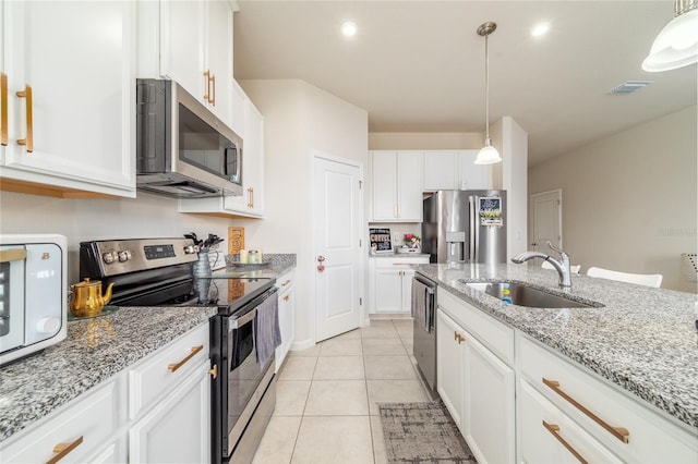 kitchen with sink, stainless steel appliances, hanging light fixtures, white cabinets, and light tile patterned floors