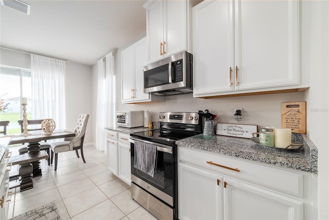 kitchen with light tile patterned flooring, light stone counters, white cabinetry, and stainless steel appliances