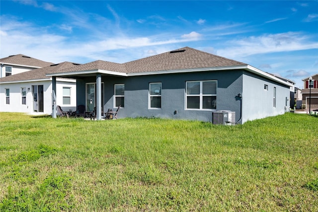 rear view of property with central air condition unit and a yard