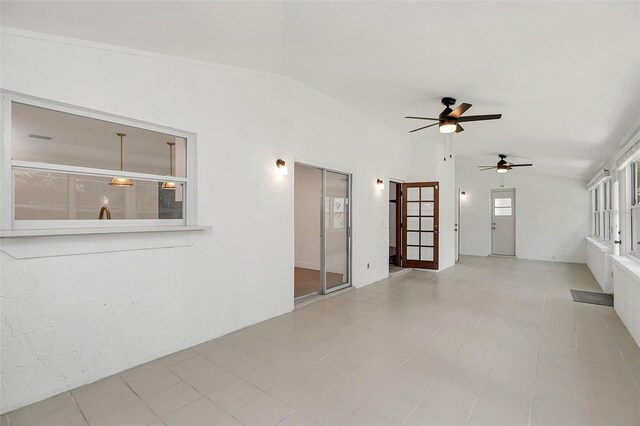 empty room with ceiling fan, light tile patterned floors, and vaulted ceiling