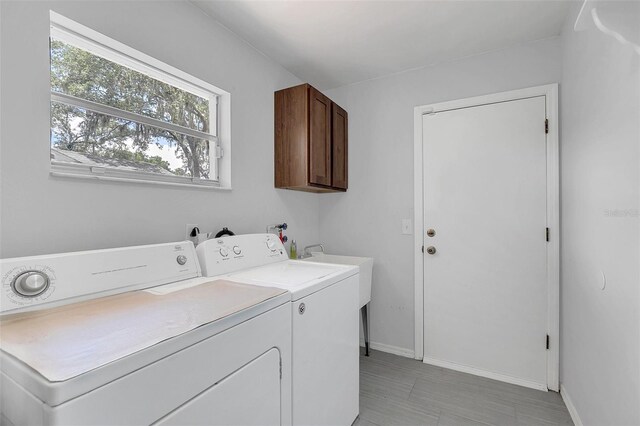 clothes washing area with cabinets and independent washer and dryer