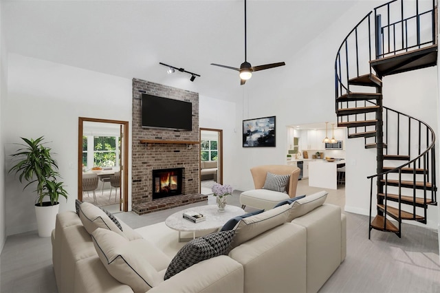 living room with a high ceiling, track lighting, a brick fireplace, and a healthy amount of sunlight