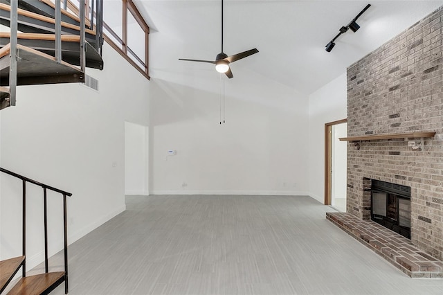 unfurnished living room featuring light hardwood / wood-style floors, high vaulted ceiling, and a brick fireplace