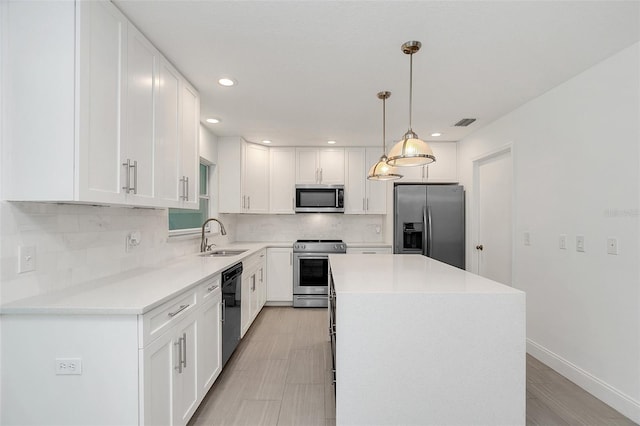 kitchen featuring pendant lighting, a center island, white cabinets, sink, and appliances with stainless steel finishes