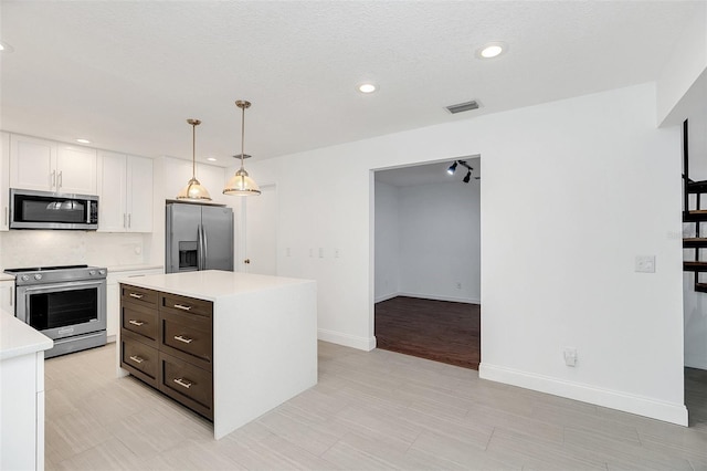 kitchen featuring a center island, stainless steel appliances, pendant lighting, a textured ceiling, and white cabinets