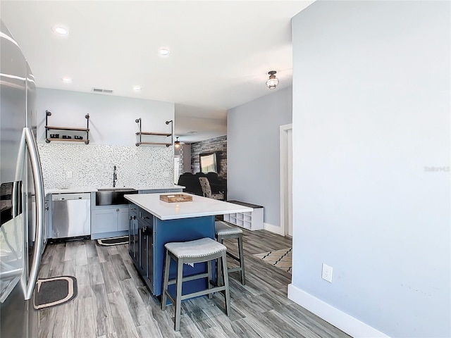 kitchen featuring light hardwood / wood-style floors, a center island, sink, a kitchen bar, and stainless steel appliances