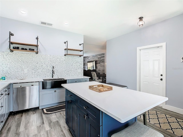 kitchen featuring decorative backsplash, a breakfast bar area, dishwasher, light wood-type flooring, and sink