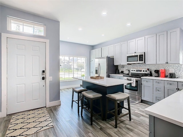 kitchen with a breakfast bar, a wealth of natural light, appliances with stainless steel finishes, and a kitchen island