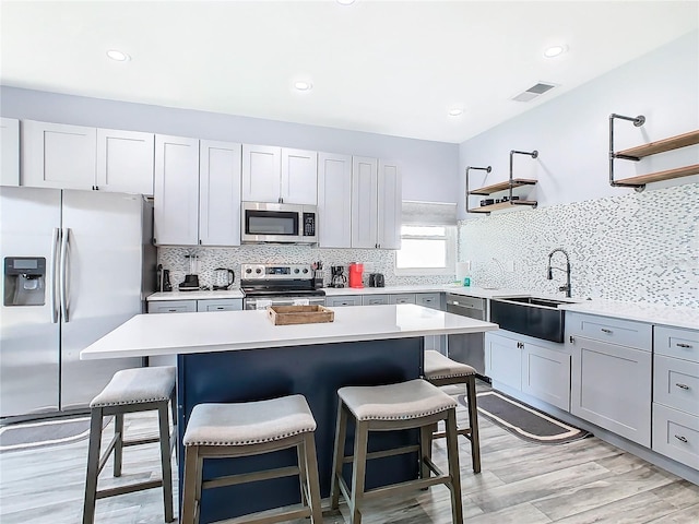 kitchen with a kitchen island, a breakfast bar area, stainless steel appliances, light wood-type flooring, and sink