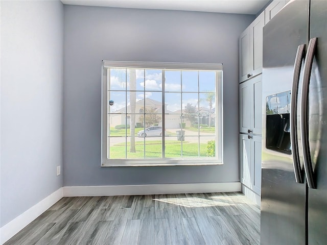 interior space with light hardwood / wood-style flooring, stainless steel fridge with ice dispenser, and white cabinets